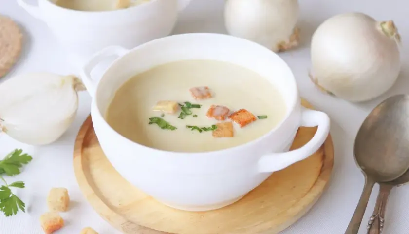 Crema reconfortante de cebolla, adornada con picatostes crujientes y perejil fresco.