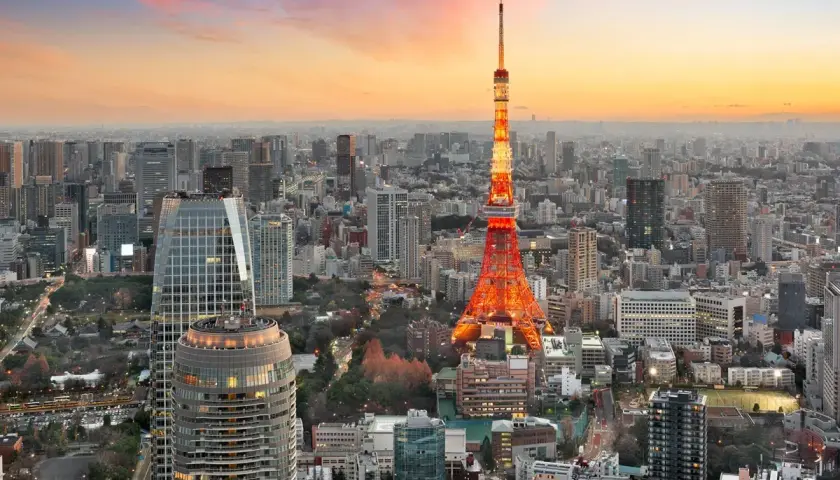 Wieżowiec Tokyo Tower oświetlony na czerwono na tle rozległego, największego miasta na świecie, Tokio, podczas zachodu słońca.