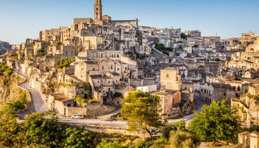 A panoramic view of Matera, Italy, showcasing its ancient cave dwellings and stone buildings cascading down a hillside, resembling a natural map.