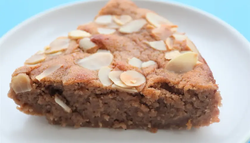 Tranche de gâteau à la crème de marron, garnie d'amandes effilées, sur une assiette blanche.