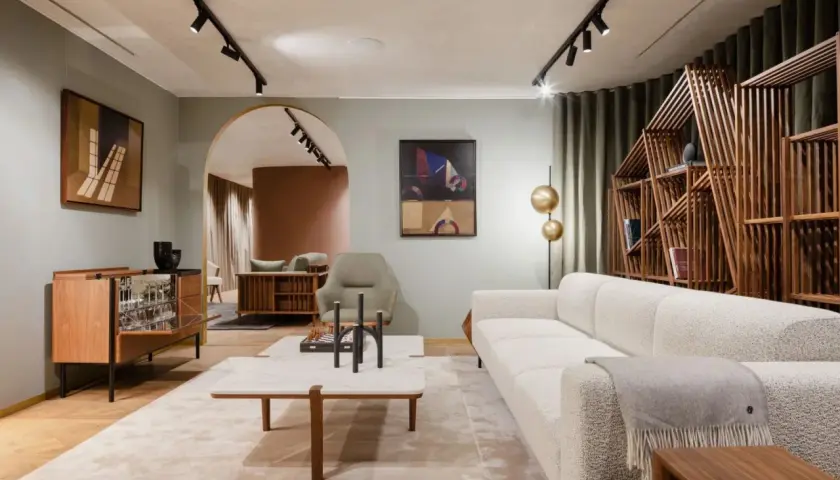 Salon lumineux avec canapé blanc, étagère en bois design et tableau abstrait. Une ambiance de deco maison moderne chic.