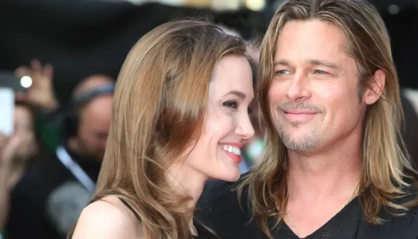 Angelina Jolie i jej mąż Brad Pitt uśmiechają się do siebie na czerwonym dywanie.