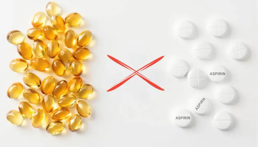 Kapsułki z omega-3 i tabletki z aspiryną, rozdzielone czerwonym krzyżykiem. Unikaj łączenia omega-3 z aspiryną.