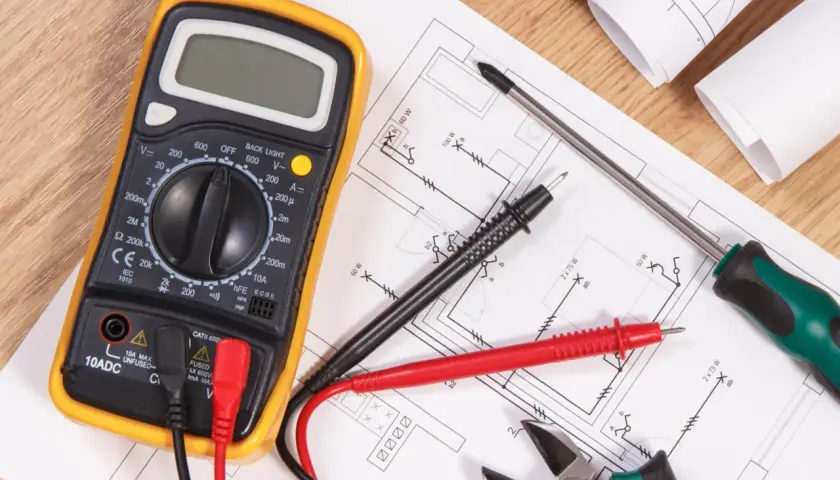 Narzędzia elektryka i schemat instalacji elektrycznej. Multimetr, śrubokręt, kombinerki i przewody gotowe do wykonania oświadczenia elektryka o wykonaniu instalacji elektrycznej.