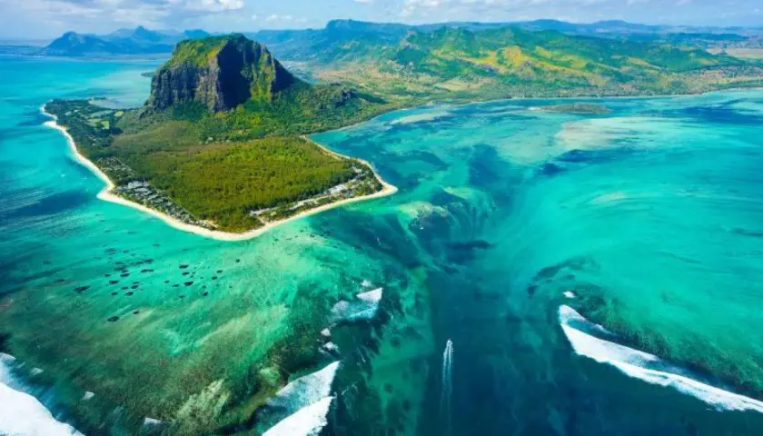 Widok z lotu ptaka na Le Morne Brabant, Mauritius, gdzie leży ta wyspa. Turkusowa woda, rafy koralowe i góra tworzą iluzję podwodnego wodospadu.