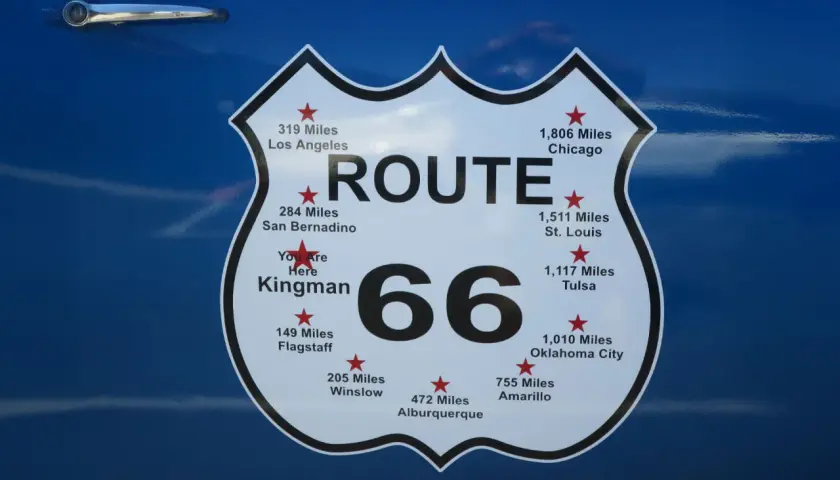 Tablica z napisem "ROUTE 66" i odległościami do miast, np. Chicago, Los Angeles. To symbol legendarnej drogi 66 w USA.