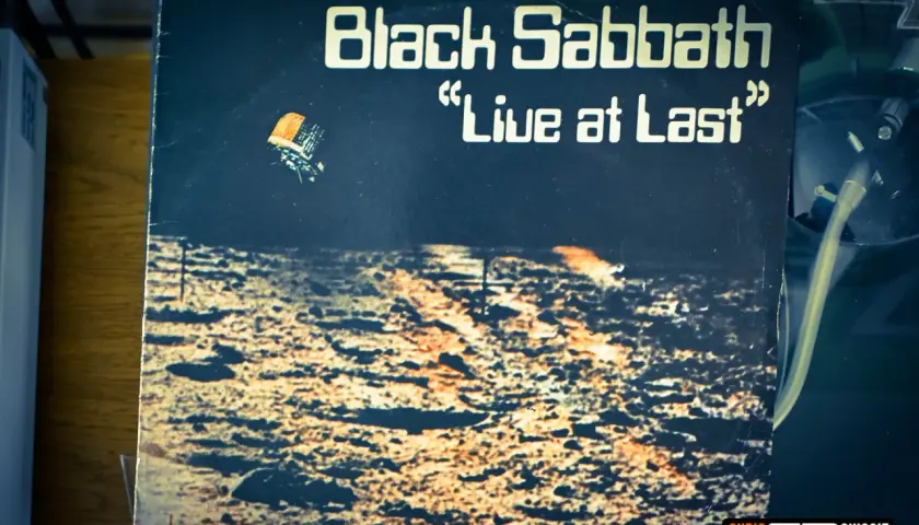 Okładka płyty "Black Sabbath 'Live at Last'". Widok z lotu ptaka na pustynny krajobraz, z małym pojazdem unoszącym się w powietrzu.