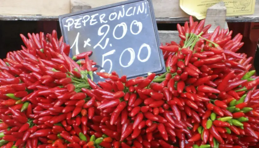 Montón de peperoncini rojos y verdes frescos, con un cartel que indica "Peperoncini 1x2.00 5.00".