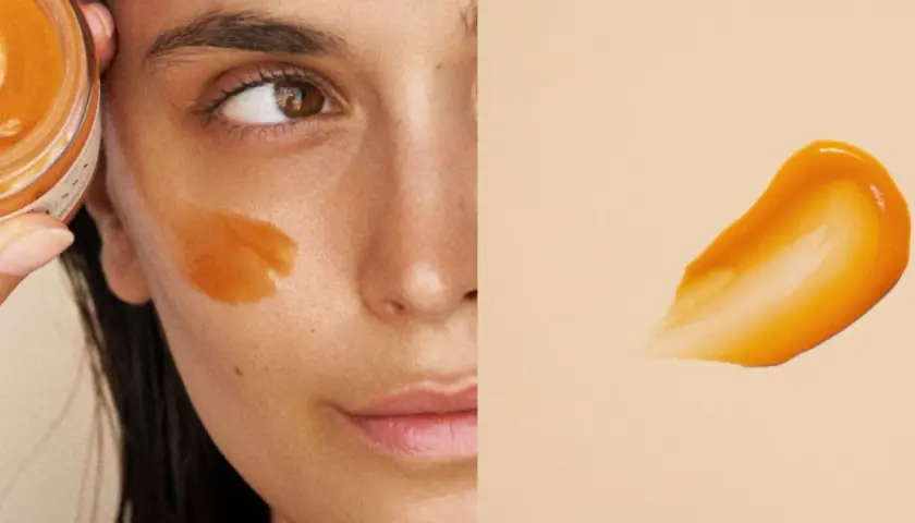 Un masque visage orangé appliqué sur la joue d'une femme. La question est : combien de temps garder un masque visage pour un soin optimal ?