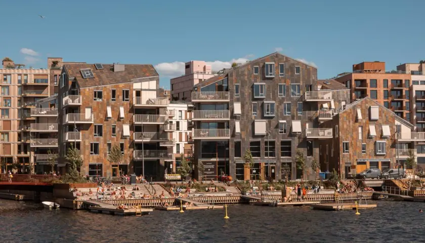 Moderne Architektur am Wasser in Oslo. Menschen entspannen sich auf Holzdecks, ein perfekter Ort für Oslo Sightseeing.