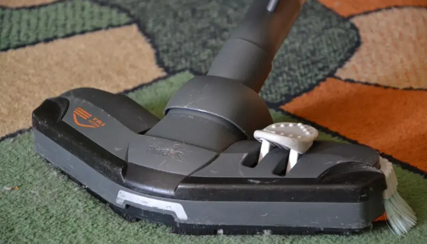 Cabezal de aspiradora sobre alfombra. Parece que la aspiradora huele mal, necesita una limpieza profunda.