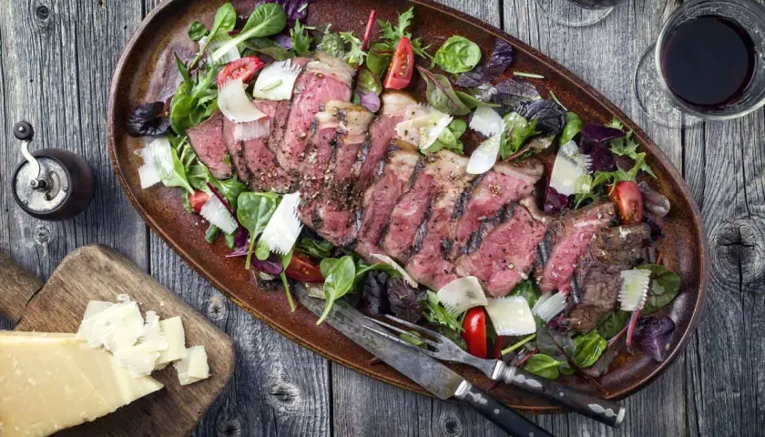 Tagliata succulenta in friggitrice ad aria, servita con insalata mista, scaglie di parmigiano e pomodorini.