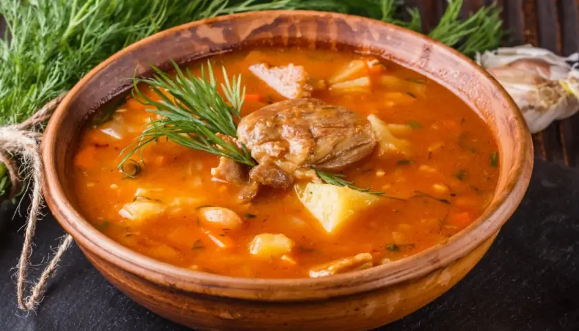 Gęsta, aromatyczna zupa ogonowa z kawałkami mięsa i ziemniaków, udekorowana świeżym koperkiem.