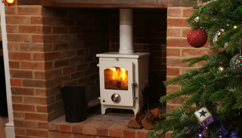 Installation d'un poêle à granulés avec conduit existant dans une cheminée en briques, décorée pour Noël.