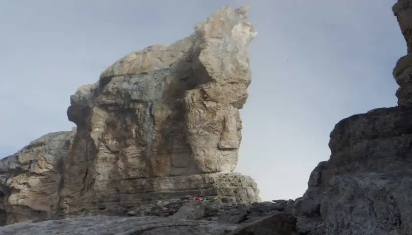 Impresionante vista de la brecha de Rolando, con imponentes formaciones rocosas y un cielo brumoso. Pequeños puntos de color sugieren la presencia de excursionistas.