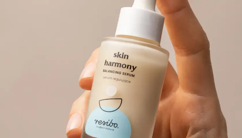 Dłoń trzyma serum Resibo Skin Harmony. W składzie znajdziesz alantoinę, która koi skórę.