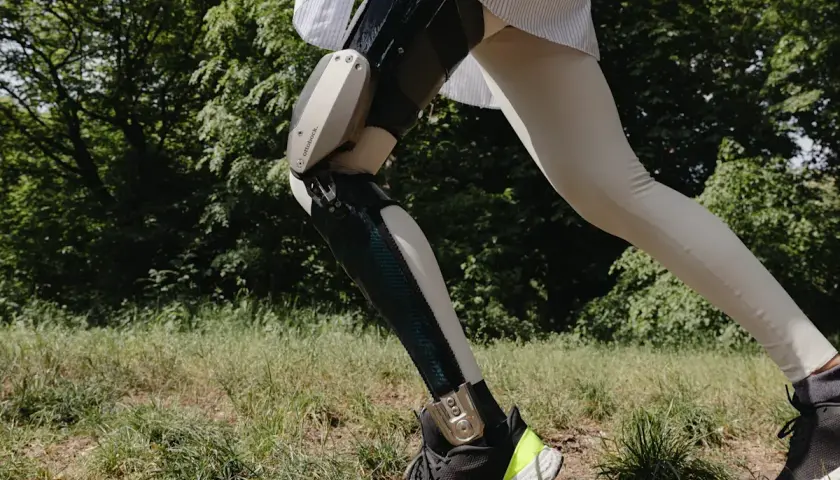 Eine Person mit einer C-Brace Orthese läuft durch grünes Gras.