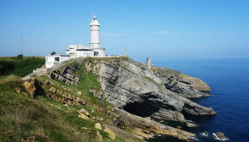 El faro de Cabo Mayor se alza sobre acantilados rocosos, vigilando el azul mar Cantábrico.