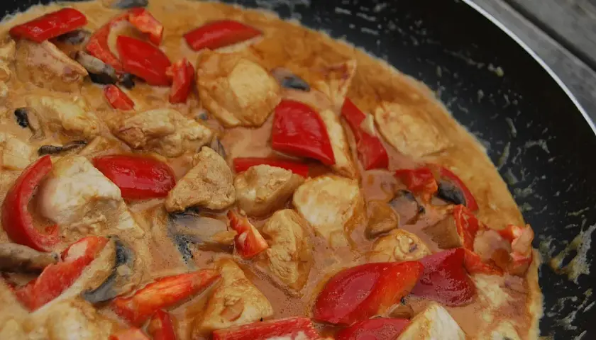 En krämig kycklinggryta med paprika och svamp i en panna, redo att serveras med ris.