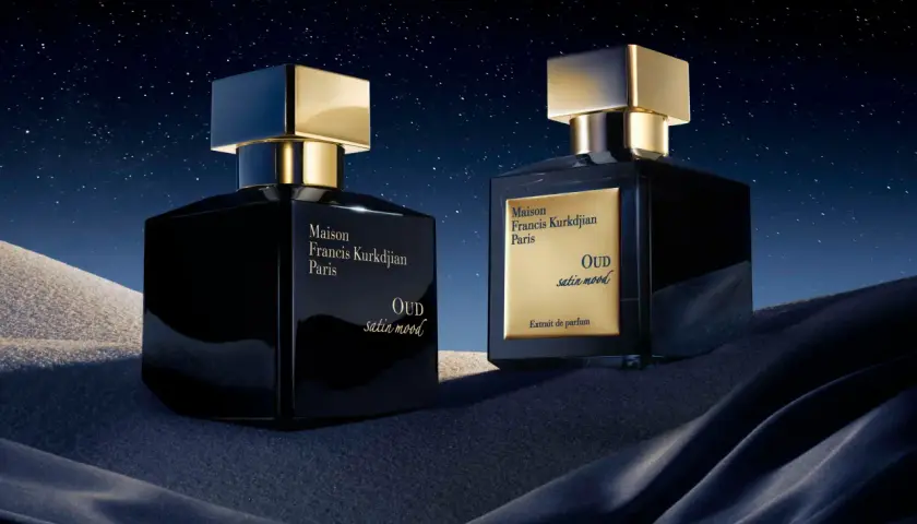 Dwa luksusowe flakony perfum Maison Francis Kurkdjian OUD satin mood na tle nocnego, gwieździstego nieba i piaszczystych wydm.