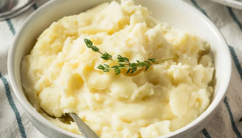 Puszyste puree ziemniaczane bez mleka, udekorowane gałązką tymianku. Idealne dla tych, którzy szukają sposobu, jak zrobić puree ziemniaczane bez mleka.