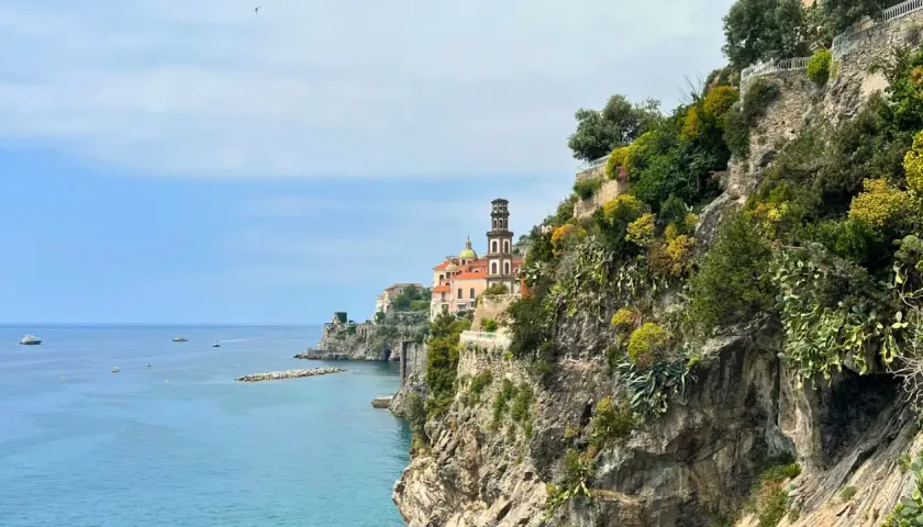 Coastal view of Amalfi with a church tower. Consider a ferry or bus for how to get from Amalfi to Naples.