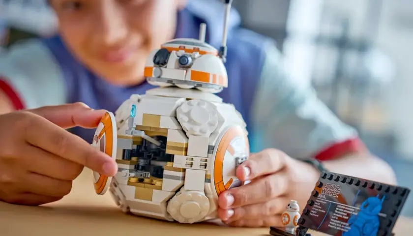 Chłopiec składa największy zestaw LEGO Star Wars - droida BB-8. Obok stoi mniejsza figurka.