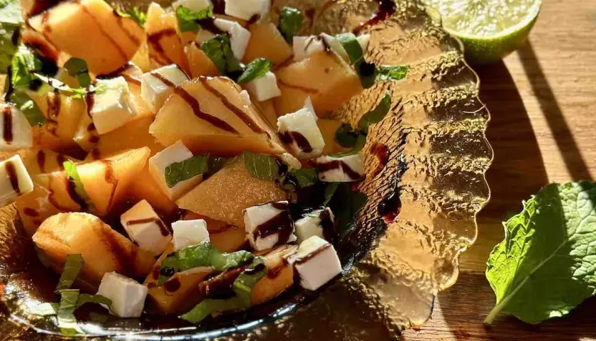 Sałatka z melona, sera feta, mięty i polewy balsamicznej w szklanej misie.