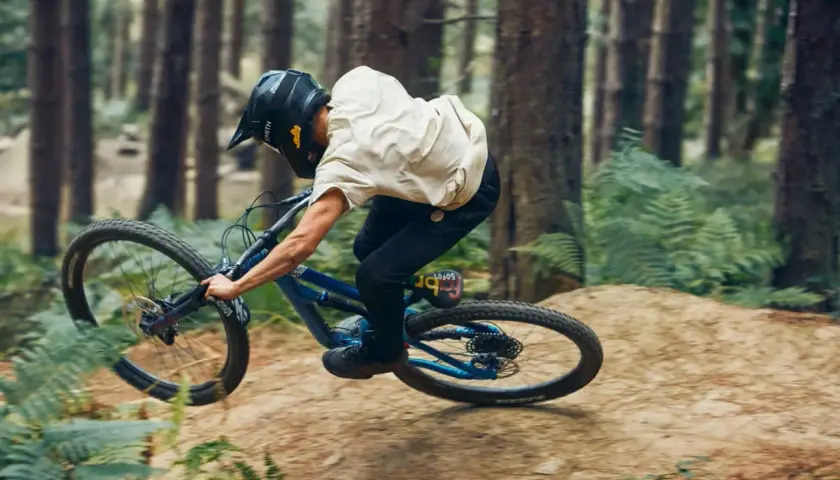 Rider in a forest, mid-air, demonstrating perfect mtb suspension tuning for a smooth landing.