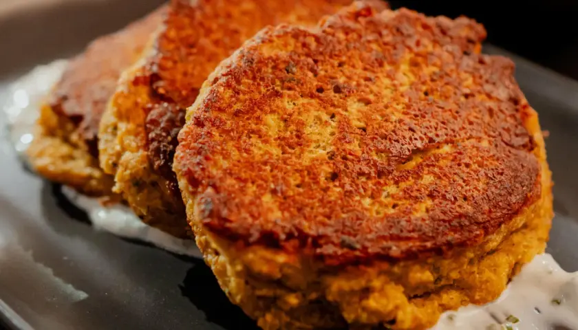 Trois galettes dorées de tortilla pois chiche, servies sur une sauce blanche crémeuse.