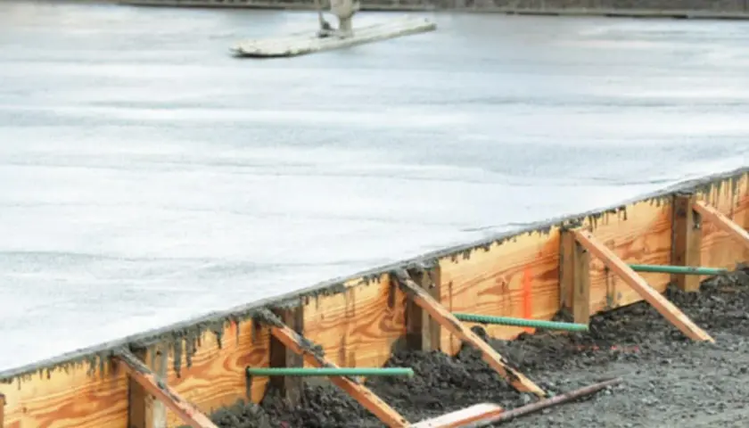 Frisch gegossener Beton wird mit einem Abzieher geglättet. Die verlorene Schalung aus Holz hält den Beton in Form, während er aushärtet.