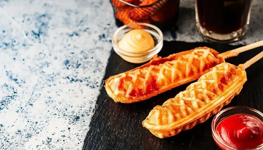 Dwa chrupiące corn dogi na patykach, podane z ketchupem i musztardą. Idealny przepis na corn doga na szybką przekąskę.