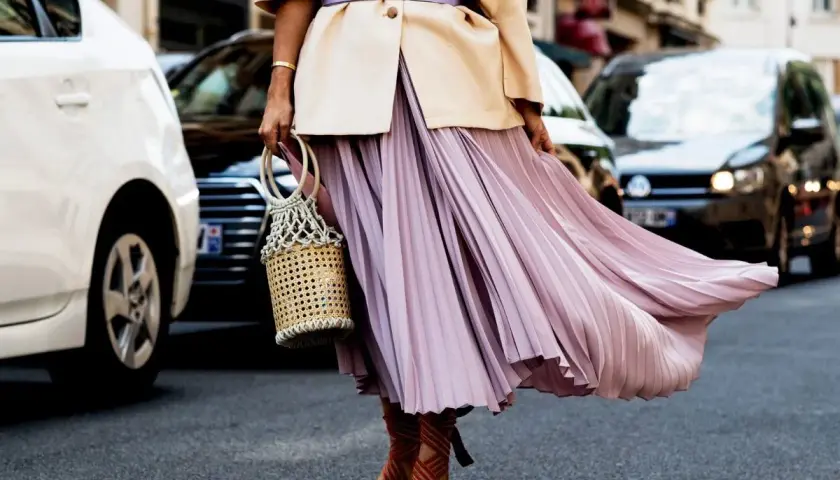 Eleganckie stylizacje z plisowaną spódnicą w pastelowym kolorze, uzupełnione wiklinową torebką i sandałami na obcasie.