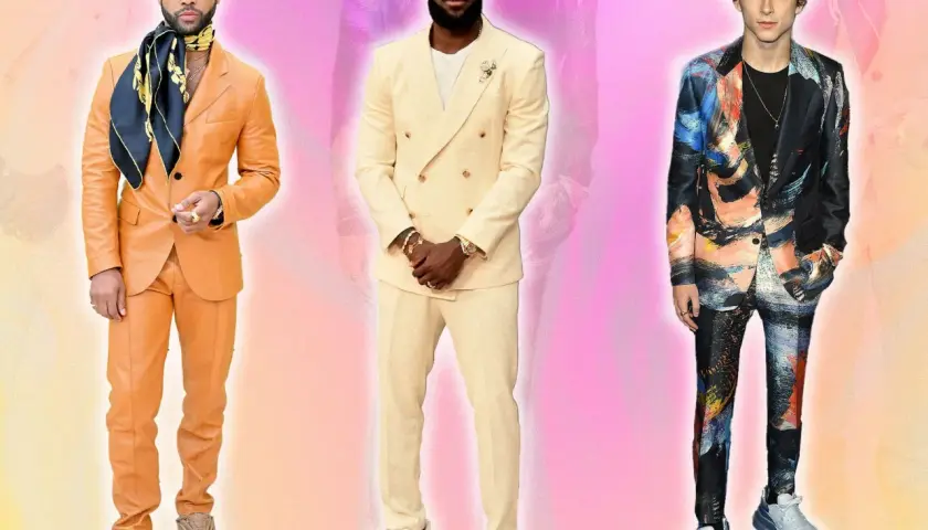 Trois hommes posent. L'un porte un costume beige et des baskets blanches.