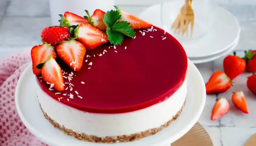 Ein köstlicher veganer Cheesecake ohne Backen, dekoriert mit frischen Erdbeeren und einem glänzenden Fruchtspiegel.