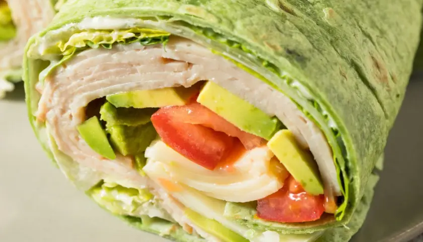Zielona tortilla z cukinii wypełniona indykiem, awokado, pomidorem i sałatą. Pyszny i zdrowy wrap.
