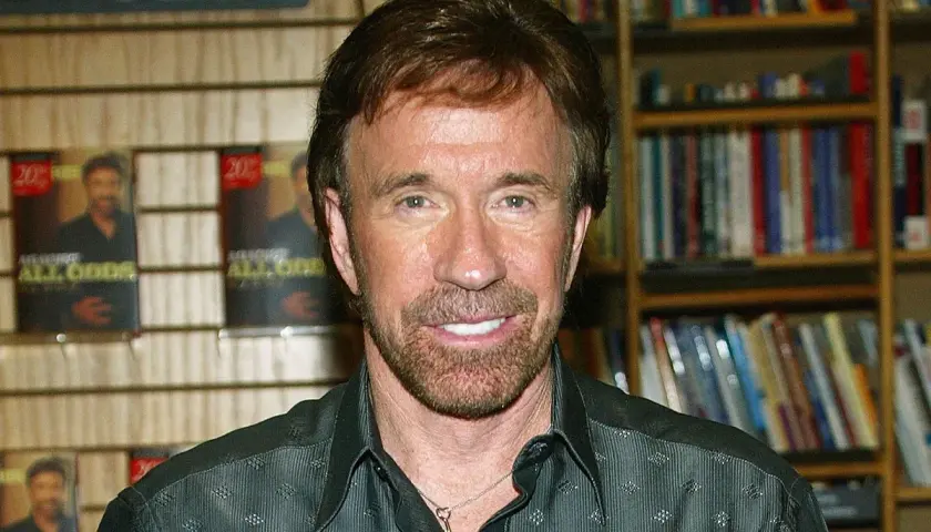 Chuck Norris, którego wiek nie ma znaczenia, bo jest niezniszczalny, pozuje na tle swoich książek.