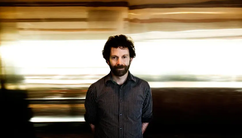 Charlie Kaufman, känd för sina unika filmer, med en drömsk, suddig bakgrund som speglar hans fantasifulla berättelser.