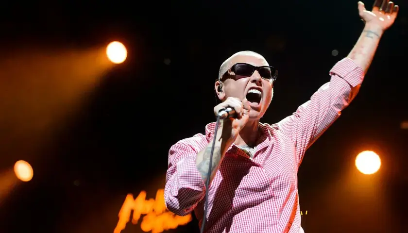 Sinéad O'Connor na koncercie, z ręką w górze, śpiewa swoje legendarne utwory.