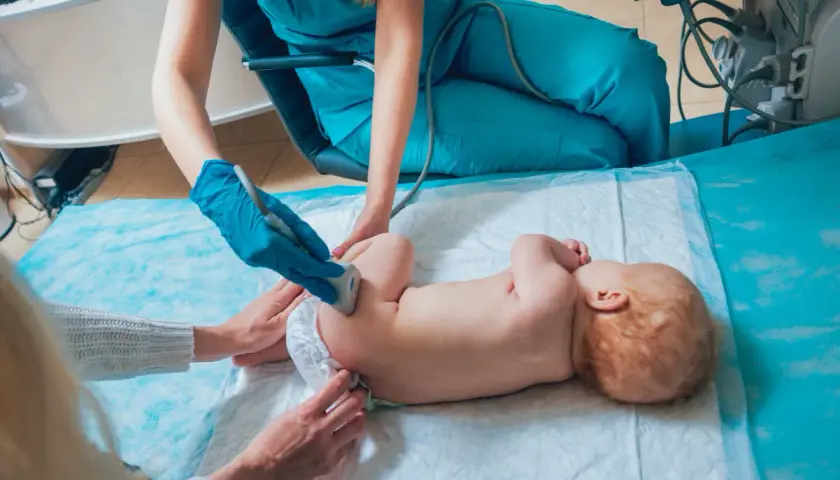 Lekarz wykonuje USG bioderek niemowlaka, sprawdzając, czy nie ma problemów ze strzelającymi stawami.