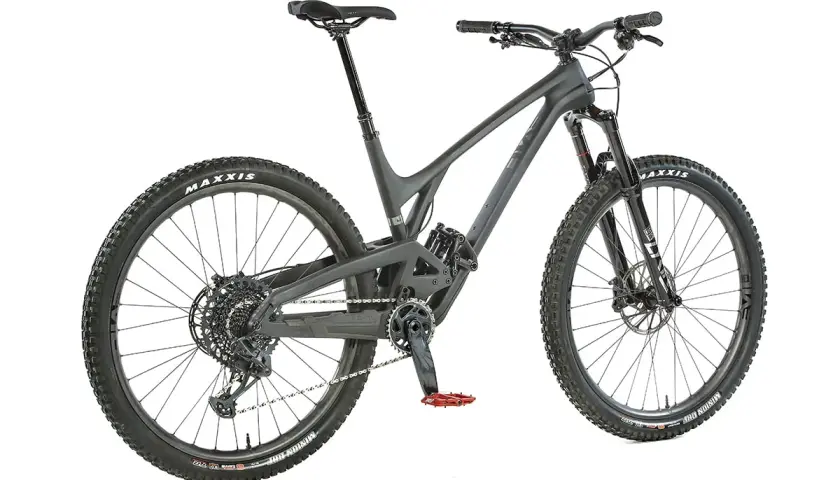 A dark grey Evil Offering mountain bike, ready for an evil offering review. Features Maxxis tires and red pedals.