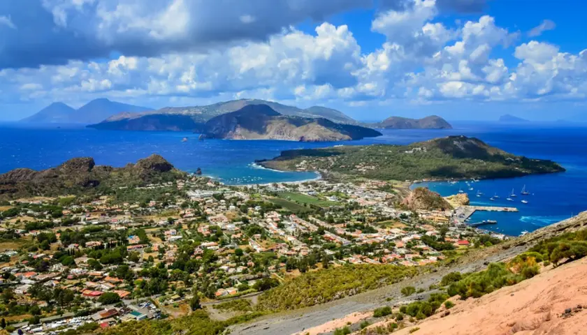 Panoramica mozzafiato delle isole Eolie, tra le isole più belle della Sicilia, con case bianche, vegetazione lussureggiante e mare blu intenso.