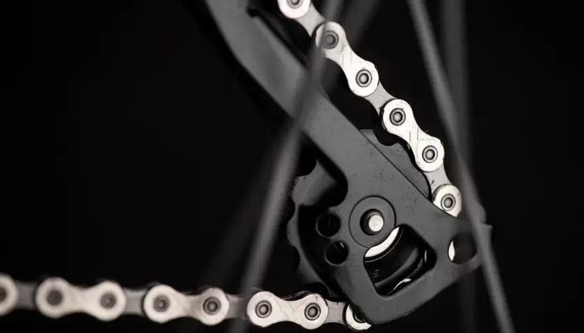 Zbliżenie na rowerowy napęd, gdzie widać mechanizm przerzutki i fragment łańcucha. Dowiedz się, jak liczyć ogniwa w łańcuchu, by zapewnić płynną jazdę.