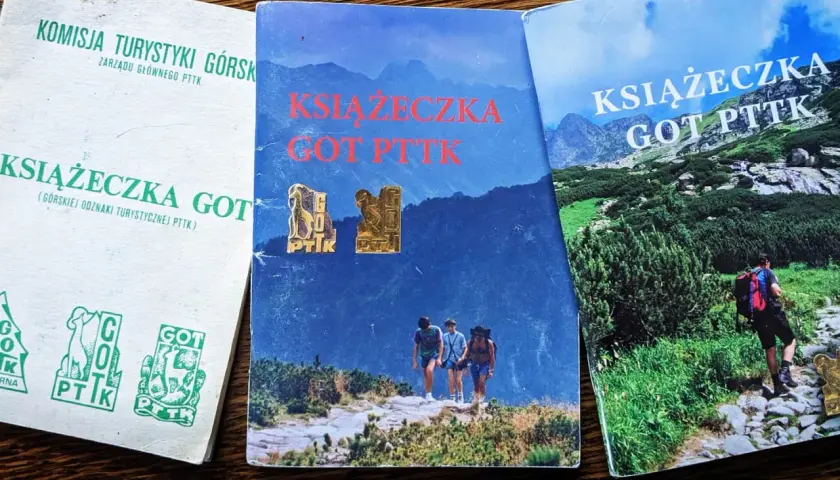 Trzy okładki książeczek GOT PTTK z odznakami. Jedna biała z zielonymi symbolami, dwie z górskimi krajobrazami i turystami.