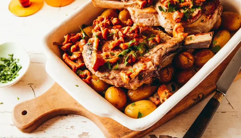 Un plat de viande blanche savoureux, des côtelettes de porc rôties avec des pommes de terre et des girolles, garni de persil frais.