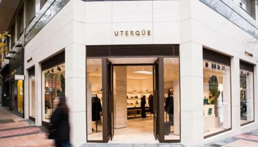 Fachada de tienda UTERQÜE con escaparates y entrada abierta. Una persona pasa por delante.