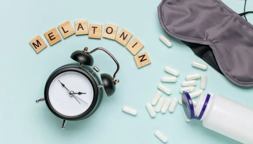 Budzik, maska na oczy i kapsułki z napisem "Melatonina" sugerują pytanie: czy melatonina jest bezpieczna?