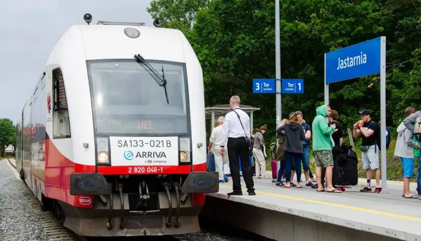 Pociąg Arriva z napisem "HEL" na stacji Jastarnia, gotowy do podróży z Gdańska na Hel. Ludzie czekają na peronie.