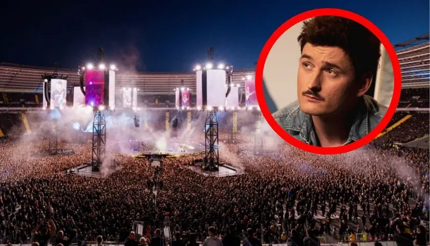 Gwiazda z wąsem na tle tłumu na największym koncercie w Polsce. Stadion wypełniony po brzegi, światła i dym tworzą niesamowitą atmosferę.