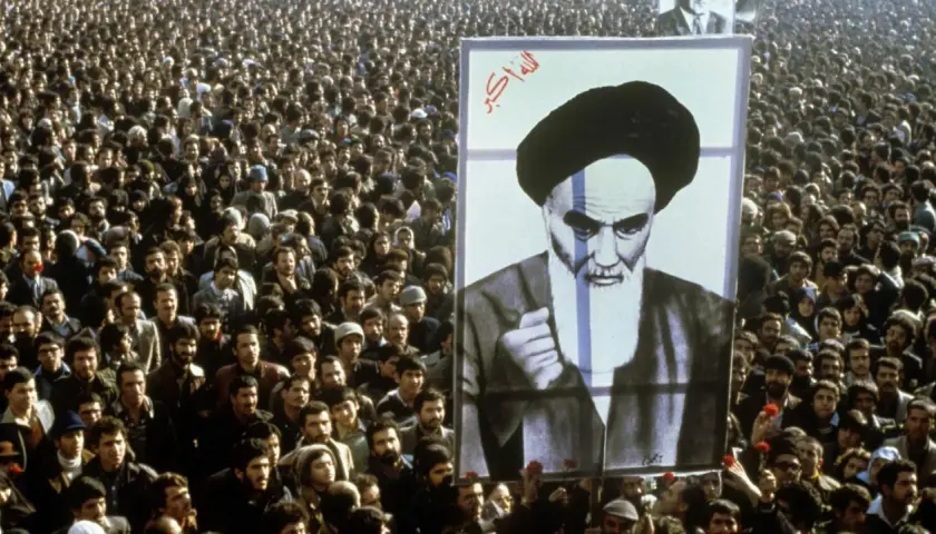 Massen jubeln bei der islamischen Revolution 1979 in Iran, ein riesiges Porträt von Ayatollah Khomeini wird hochgehalten.
